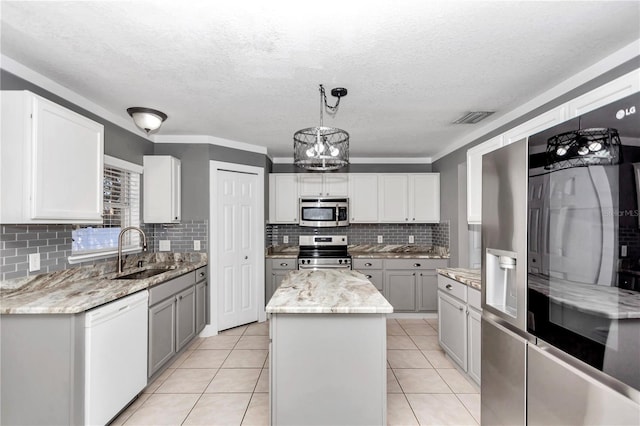 kitchen featuring decorative light fixtures, a kitchen island, sink, appliances with stainless steel finishes, and light tile patterned floors