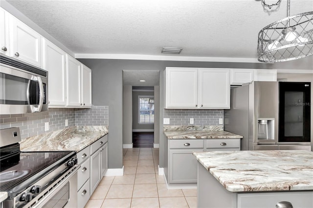 kitchen with white cabinets, a textured ceiling, appliances with stainless steel finishes, and tasteful backsplash