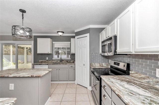 kitchen with a wealth of natural light, white cabinets, appliances with stainless steel finishes, sink, and light tile patterned floors