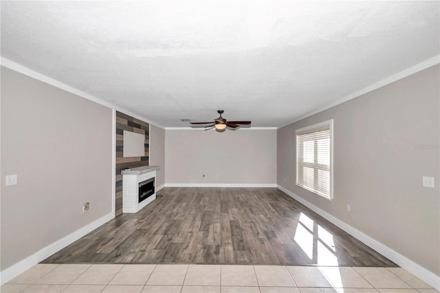 unfurnished living room with ceiling fan, a textured ceiling, crown molding, and light tile patterned flooring