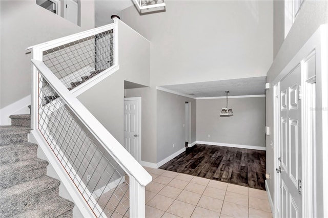 tiled foyer entrance featuring a towering ceiling and crown molding