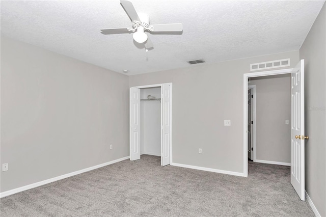 unfurnished bedroom featuring ceiling fan, light colored carpet, and a textured ceiling