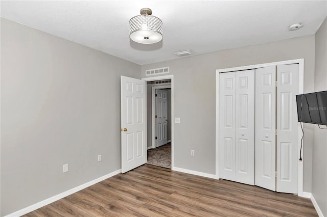 unfurnished bedroom featuring a textured ceiling, a closet, and dark hardwood / wood-style flooring