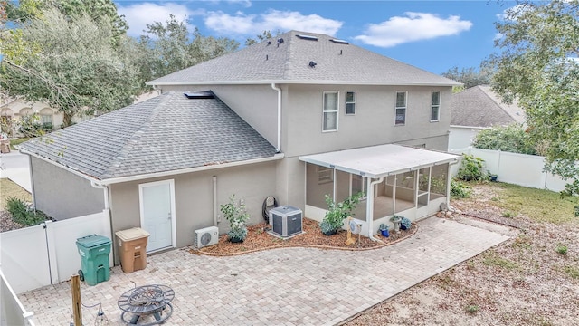 rear view of house featuring a sunroom, a patio, ac unit, a fire pit, and central air condition unit