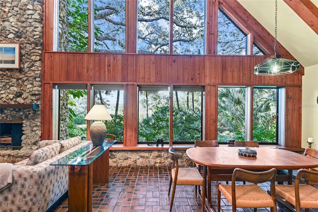 sunroom / solarium with lofted ceiling with beams, a stone fireplace, and plenty of natural light