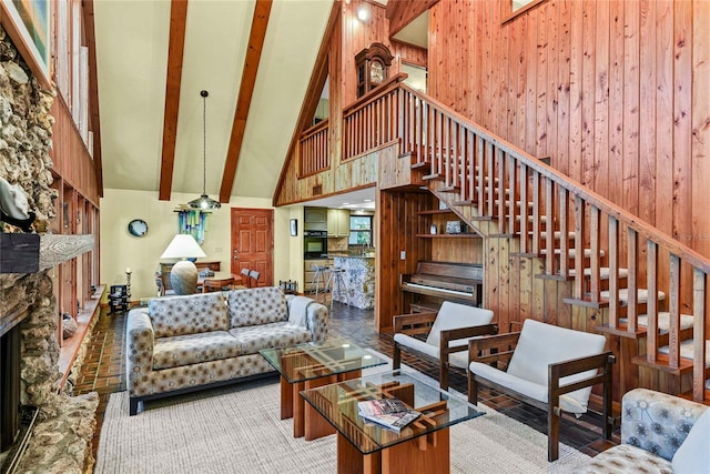 living room featuring beam ceiling, high vaulted ceiling, a stone fireplace, and wood walls