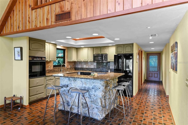 kitchen with a breakfast bar, black appliances, sink, decorative backsplash, and a kitchen island