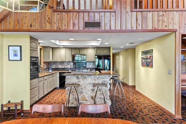 kitchen featuring black appliances, sink, dark stone countertops, tasteful backsplash, and a breakfast bar area