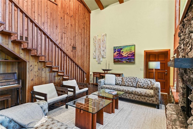 living room with wooden walls, beamed ceiling, and high vaulted ceiling