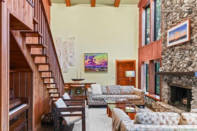 living room with a fireplace, a towering ceiling, and beamed ceiling