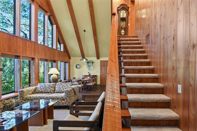 stairway featuring wooden walls, beamed ceiling, and high vaulted ceiling