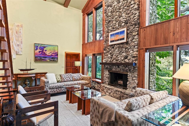 carpeted living room with a stone fireplace, wood walls, beamed ceiling, and high vaulted ceiling