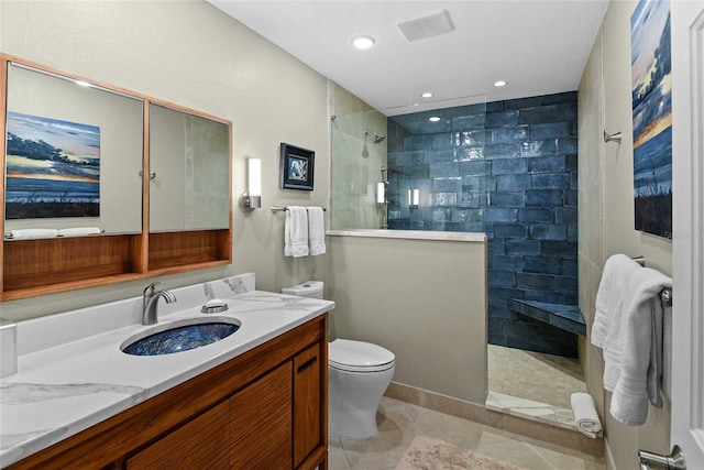 bathroom with a tile shower, tile patterned floors, vanity, and toilet