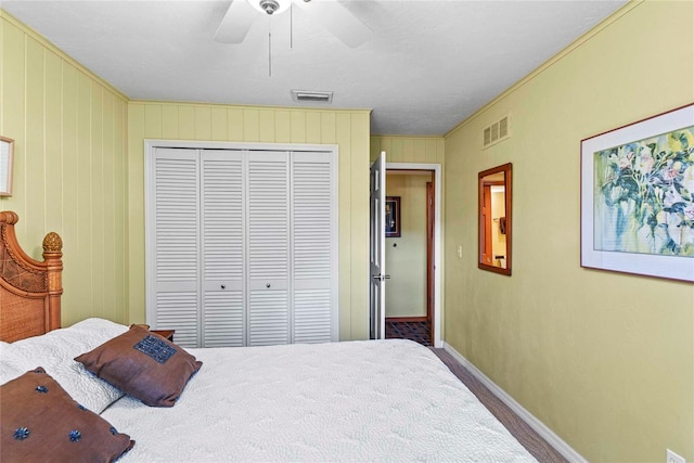 bedroom featuring crown molding, a closet, wooden walls, and ceiling fan