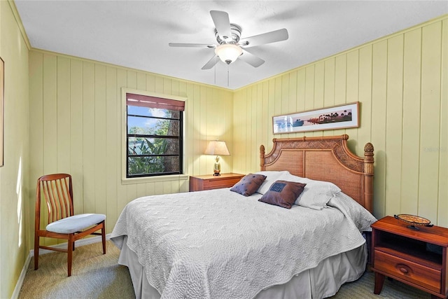 carpeted bedroom with ceiling fan and wooden walls