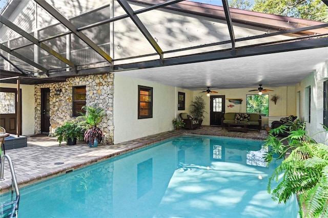 view of pool with outdoor lounge area, glass enclosure, ceiling fan, and a patio area