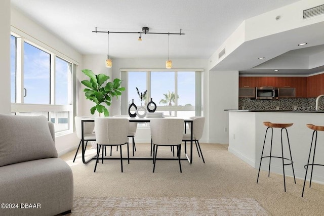 kitchen with decorative backsplash, decorative light fixtures, and light colored carpet