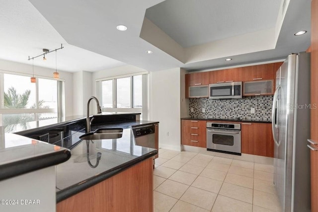 kitchen with appliances with stainless steel finishes, backsplash, a raised ceiling, sink, and hanging light fixtures