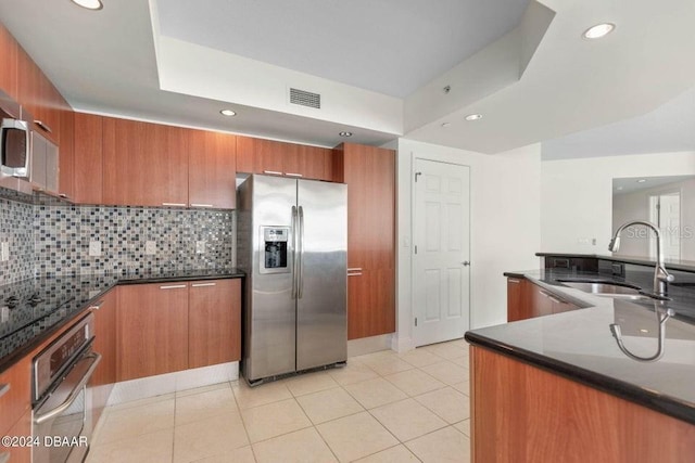 kitchen featuring oven, sink, stainless steel refrigerator with ice dispenser, tasteful backsplash, and light tile patterned flooring