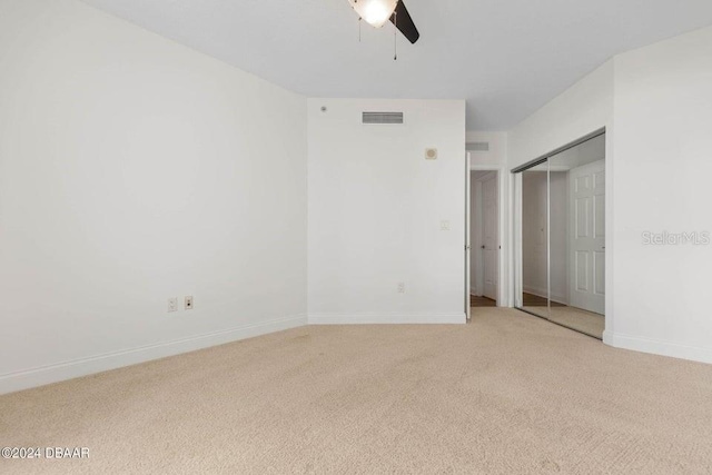 unfurnished bedroom featuring ceiling fan, light colored carpet, and a closet