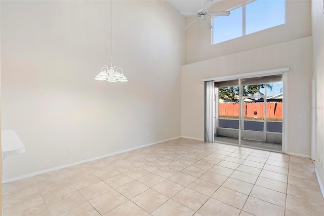 tiled empty room with ceiling fan with notable chandelier and a towering ceiling