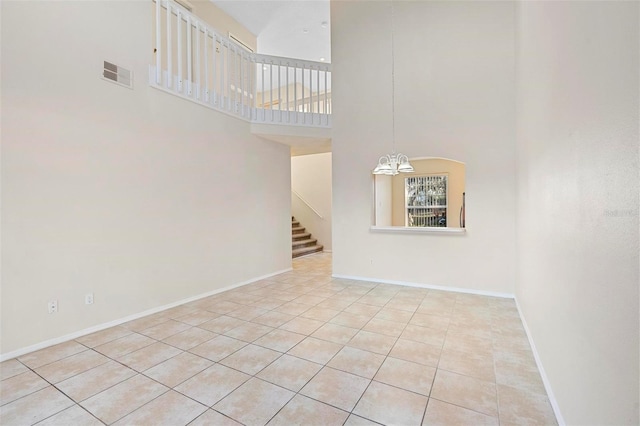 unfurnished living room featuring light tile patterned floors, a towering ceiling, and a notable chandelier