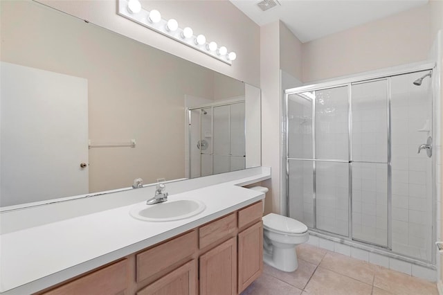 bathroom featuring toilet, vanity, tile patterned flooring, and a shower with door