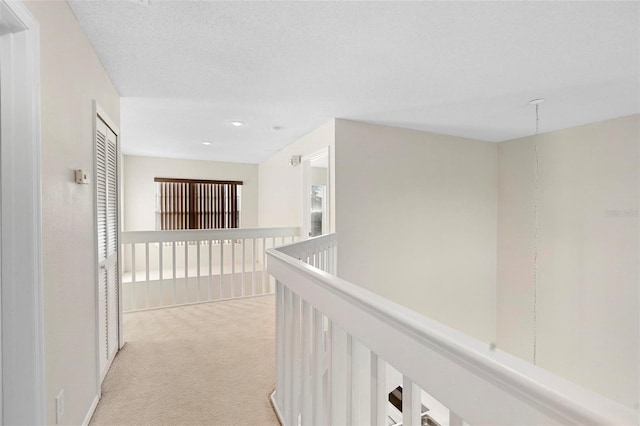 corridor featuring light carpet and a textured ceiling