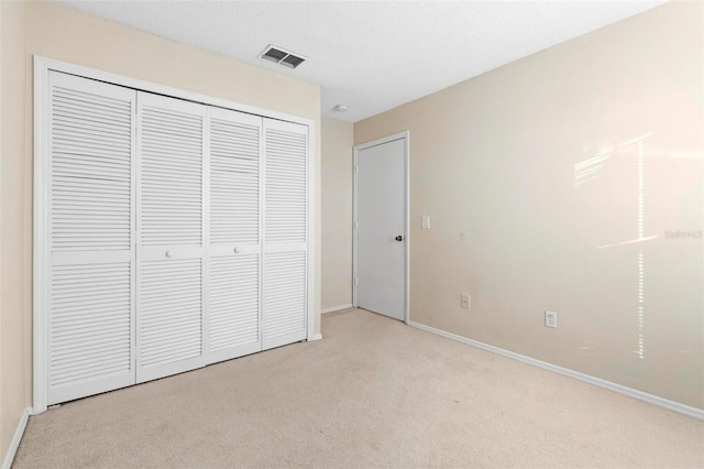 unfurnished bedroom with light carpet and a closet