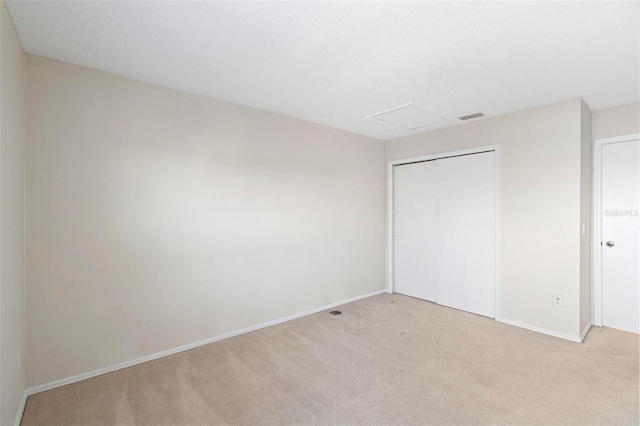 unfurnished bedroom featuring light carpet and a closet