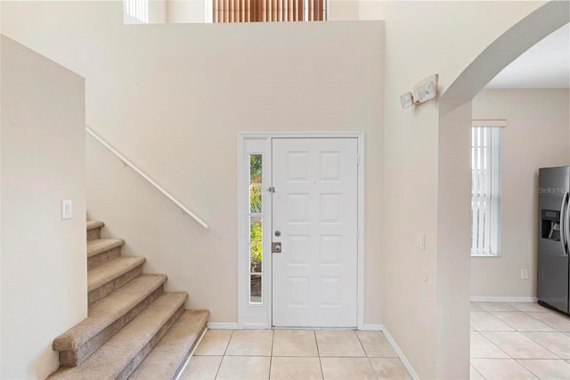 foyer entrance featuring light tile patterned floors and a towering ceiling