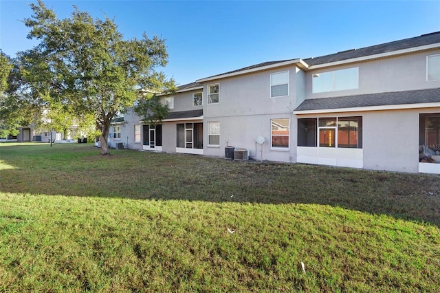 rear view of property featuring cooling unit and a lawn