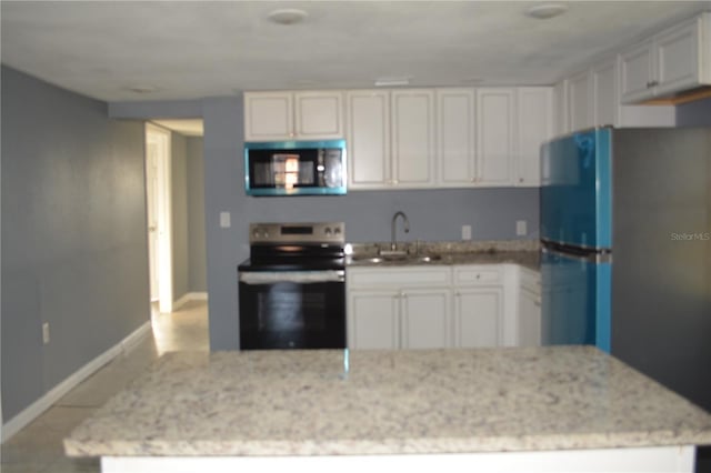 kitchen with light tile patterned floors, stainless steel appliances, white cabinets, light stone counters, and sink