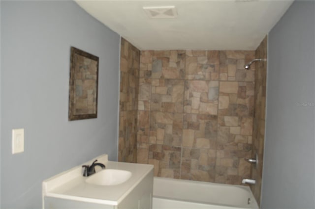 bathroom with tiled shower / bath and vanity