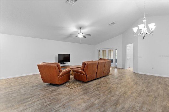 living room with ceiling fan with notable chandelier, light hardwood / wood-style floors, and vaulted ceiling