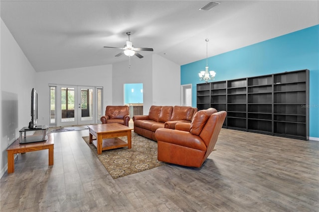 living room with french doors, ceiling fan with notable chandelier, wood-type flooring, and vaulted ceiling