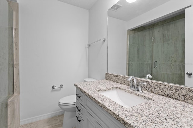 bathroom featuring vanity, toilet, a shower with door, tile patterned floors, and a textured ceiling