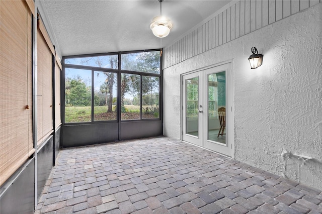 unfurnished sunroom featuring a healthy amount of sunlight, french doors, and vaulted ceiling