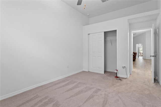 unfurnished bedroom featuring lofted ceiling, light carpet, a closet, and ceiling fan