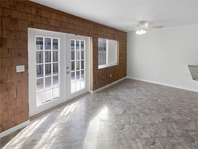 unfurnished living room with wooden walls, french doors, and ceiling fan