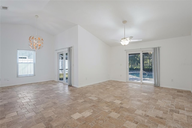 unfurnished room with plenty of natural light, ceiling fan with notable chandelier, and vaulted ceiling