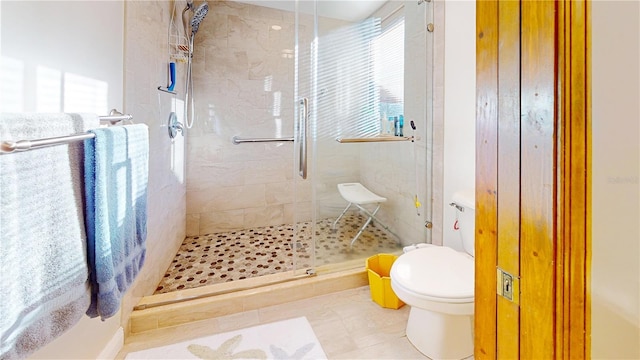 bathroom featuring toilet, walk in shower, and tile patterned flooring