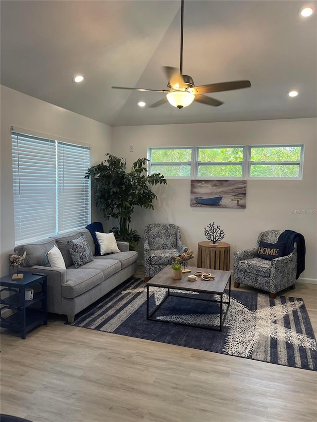 living room with ceiling fan, light wood-type flooring, a wealth of natural light, and vaulted ceiling