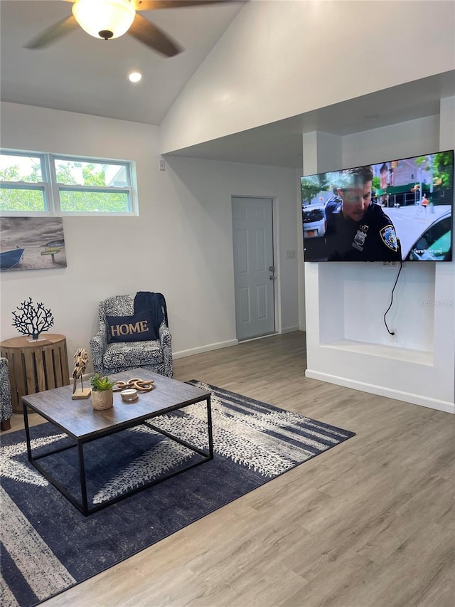 living room with hardwood / wood-style flooring, ceiling fan, and vaulted ceiling