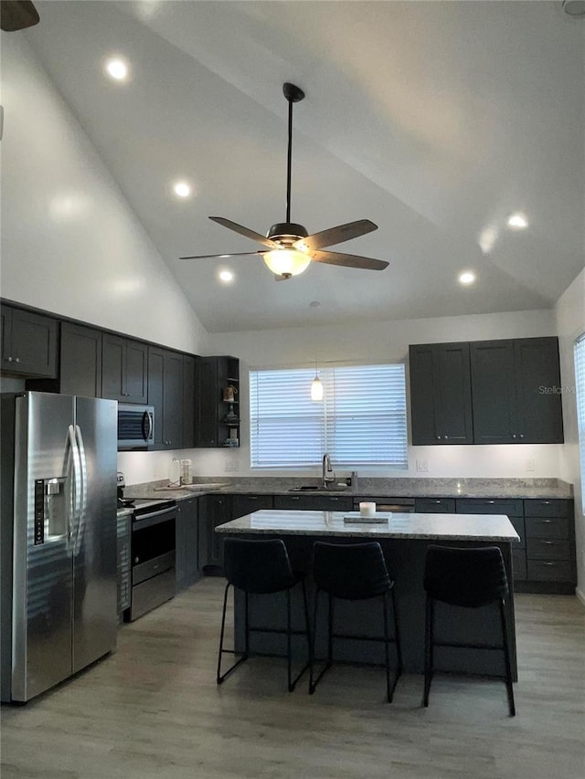 kitchen with a kitchen bar, appliances with stainless steel finishes, high vaulted ceiling, and a kitchen island