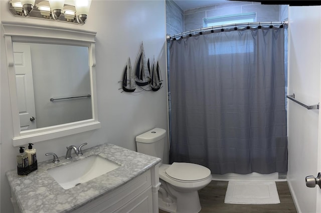 bathroom with toilet, hardwood / wood-style floors, vanity, and walk in shower