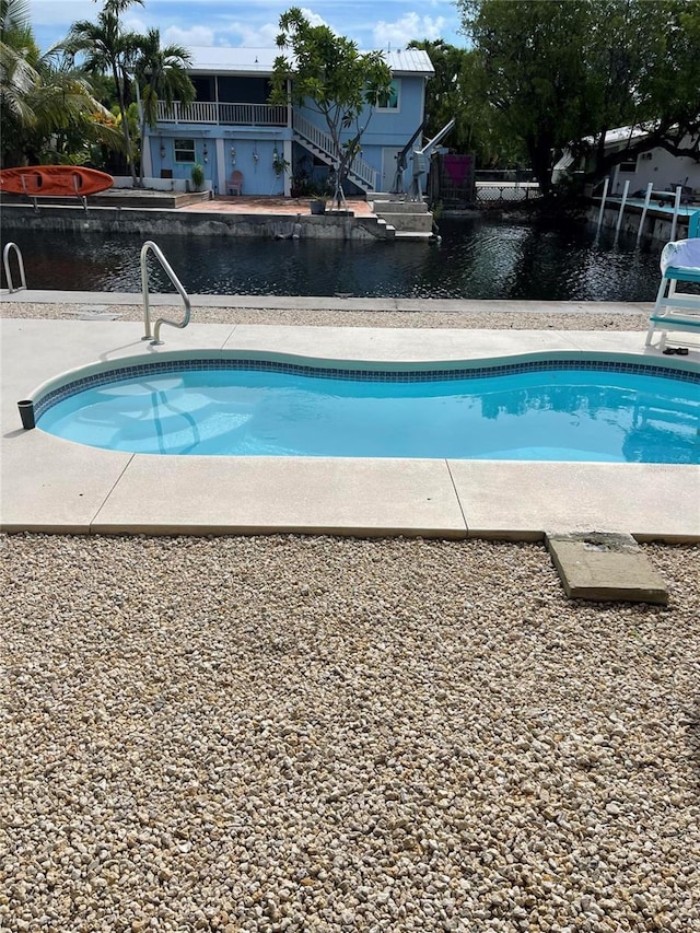 view of pool featuring a water view and a patio