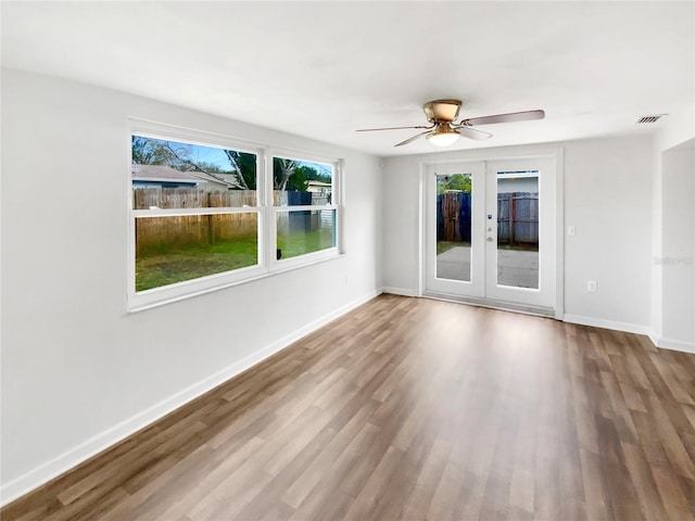 unfurnished room featuring hardwood / wood-style flooring, ceiling fan, and french doors