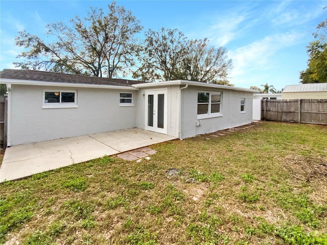 rear view of property featuring french doors, a patio area, and a lawn