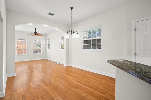 unfurnished dining area with hardwood / wood-style floors and ceiling fan with notable chandelier